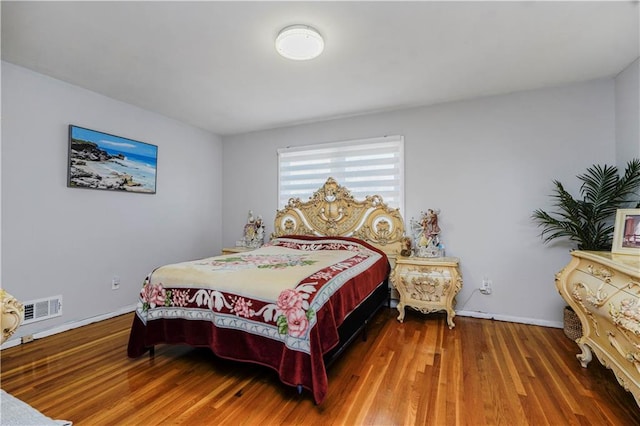 bedroom featuring wood finished floors, visible vents, and baseboards