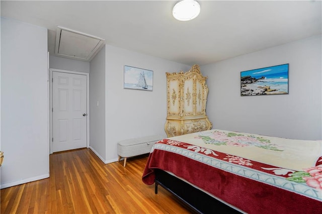 bedroom featuring baseboards, attic access, and wood finished floors