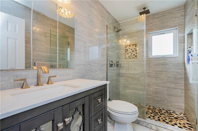 full bathroom featuring toilet, a tile shower, tile walls, a chandelier, and vanity