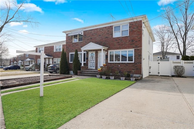 view of front of property featuring a front lawn, a gate, fence, and brick siding