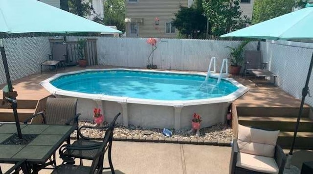 view of pool with a wooden deck and a fenced backyard