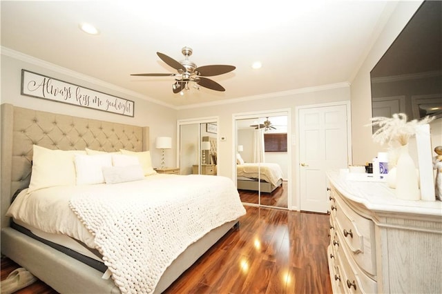 bedroom with ceiling fan, multiple closets, dark wood-type flooring, and ornamental molding