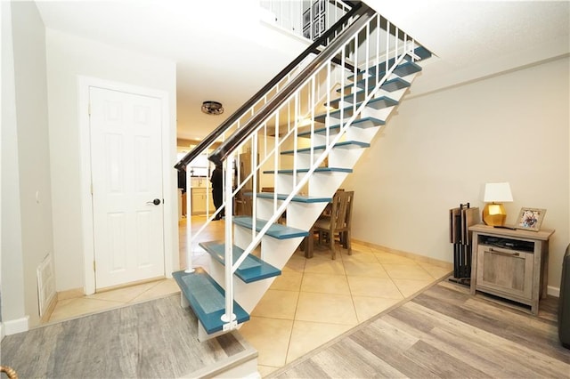 stairway with tile patterned floors, baseboards, and visible vents