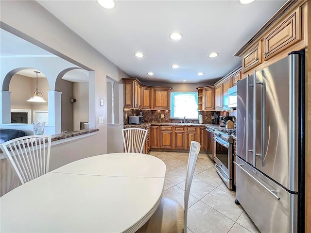 kitchen featuring recessed lighting, a sink, appliances with stainless steel finishes, backsplash, and brown cabinetry