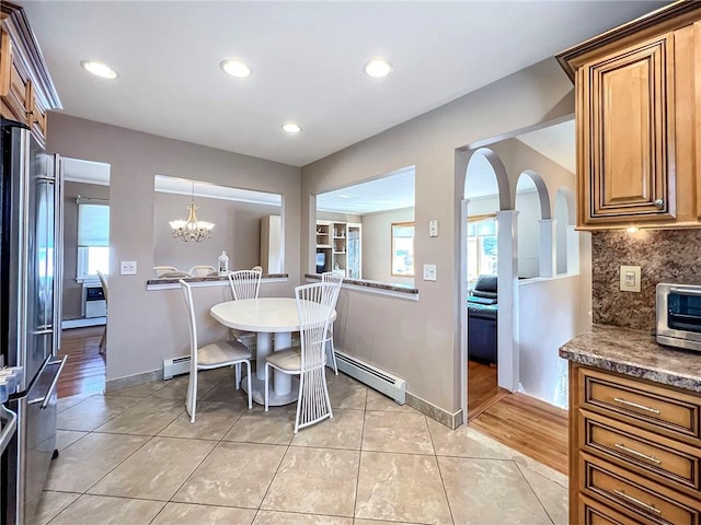 dining room featuring light tile patterned flooring, a toaster, a baseboard heating unit, baseboards, and an inviting chandelier