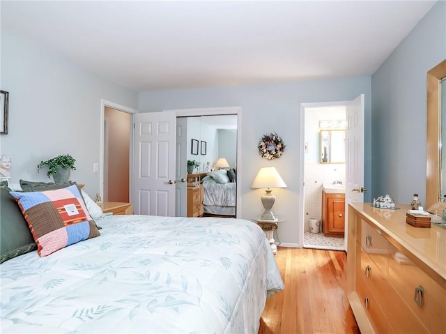 bedroom with a closet, ensuite bath, and light wood-style floors