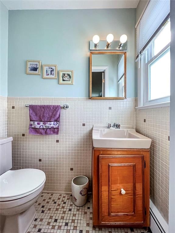 bathroom featuring toilet, a baseboard radiator, tile walls, and vanity