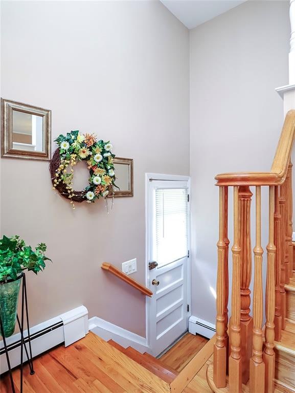 staircase with baseboards, a baseboard heating unit, and wood finished floors