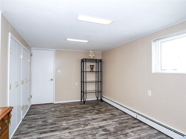 spare room with a baseboard heating unit, ornamental molding, and wood finished floors