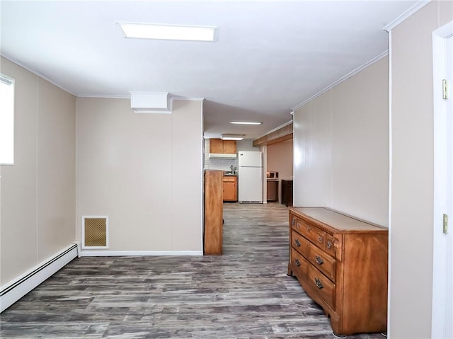 empty room with ornamental molding, a baseboard radiator, wood finished floors, and visible vents