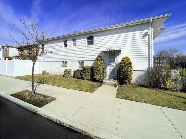 view of front facade featuring a front yard and fence