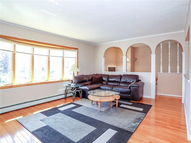 living room featuring a baseboard heating unit, wood finished floors, arched walkways, and crown molding