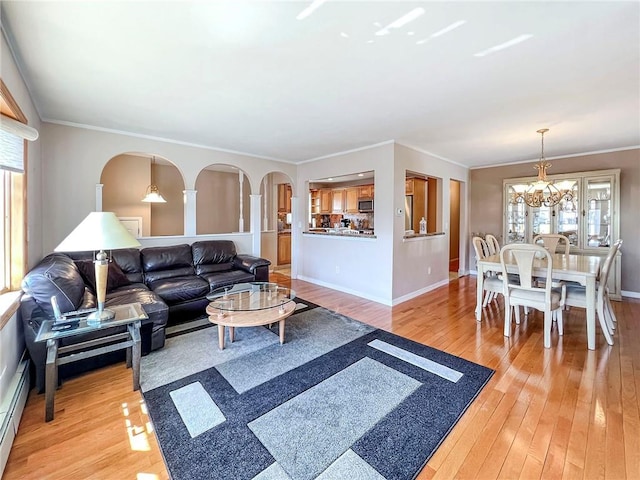 living area with light wood-style floors, a chandelier, ornamental molding, and baseboards