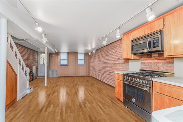 kitchen featuring light countertops, light wood-style flooring, radiator heating unit, and stainless steel appliances