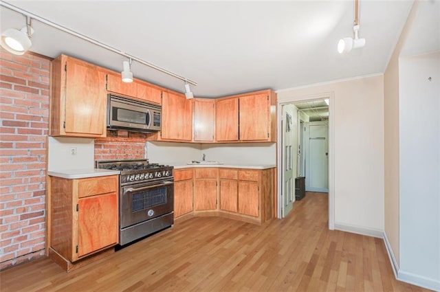 kitchen featuring light countertops, light wood-style floors, baseboards, and appliances with stainless steel finishes