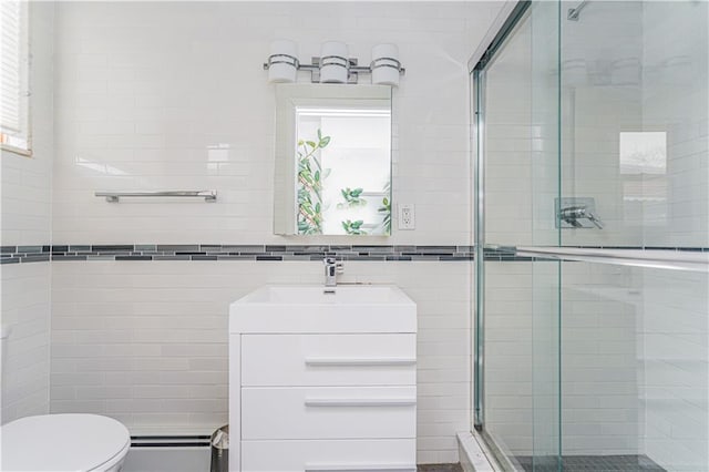 full bath featuring a baseboard radiator, toilet, vanity, tile walls, and a stall shower