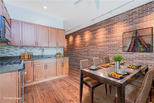 kitchen with brick wall, a sink, light wood-type flooring, double oven range, and backsplash