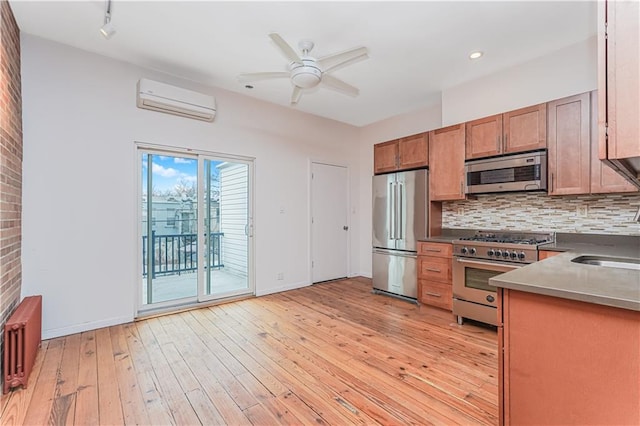 kitchen with light wood-type flooring, tasteful backsplash, appliances with stainless steel finishes, and a wall mounted AC