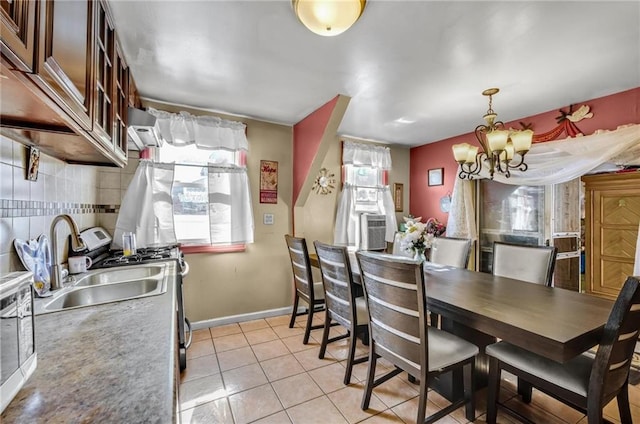 dining space with baseboards, a notable chandelier, and light tile patterned floors