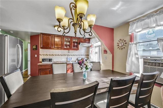 kitchen with plenty of natural light, freestanding refrigerator, under cabinet range hood, and a chandelier