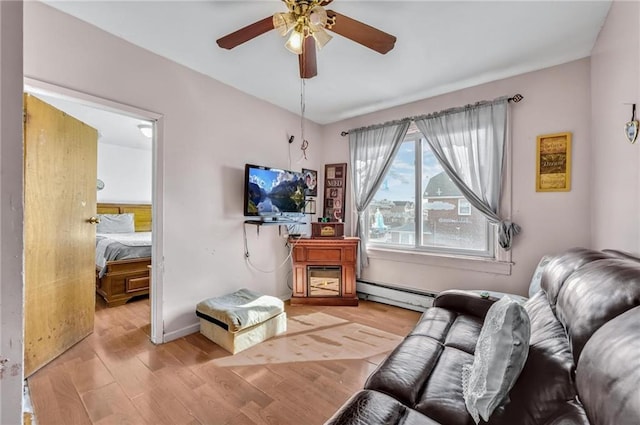 living area with ceiling fan, a baseboard heating unit, and wood finished floors