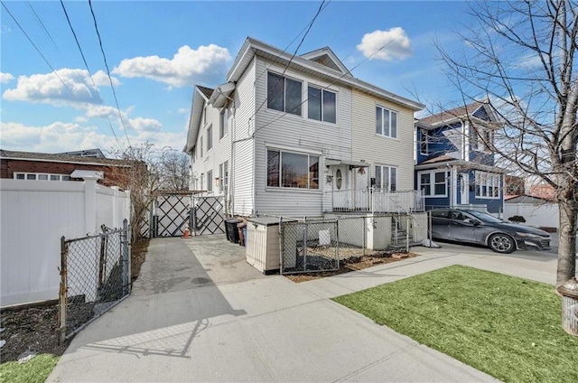 view of front of home with a gate, driveway, fence private yard, and a front lawn