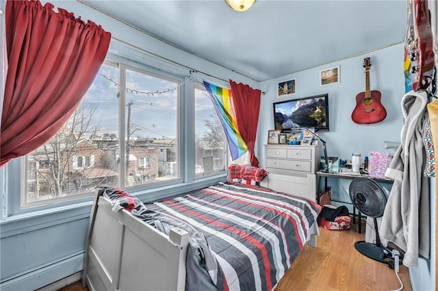 bedroom featuring wood finished floors and baseboard heating