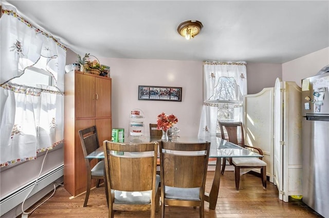 dining space with a baseboard heating unit and wood finished floors