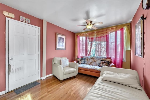 living room with baseboards, light wood finished floors, and ceiling fan
