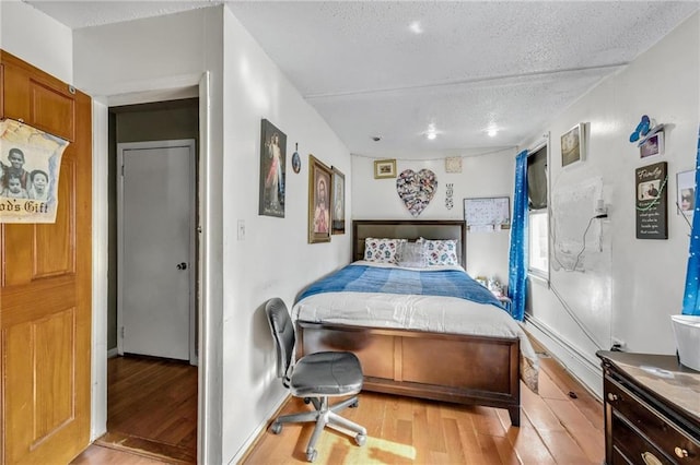 bedroom with light wood-type flooring and a textured ceiling