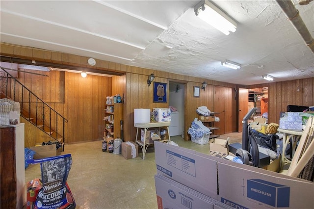 finished basement with wooden walls, stairway, and tile patterned floors