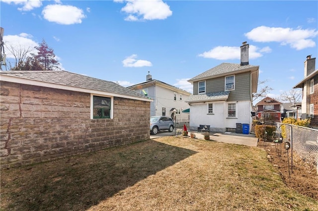 back of house featuring a patio area, a chimney, fence, and a yard