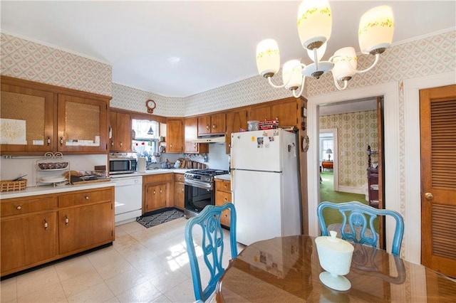 kitchen featuring under cabinet range hood, light countertops, appliances with stainless steel finishes, brown cabinets, and wallpapered walls