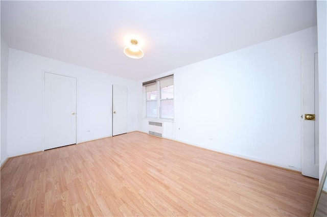 unfurnished room with radiator heating unit and light wood-style flooring