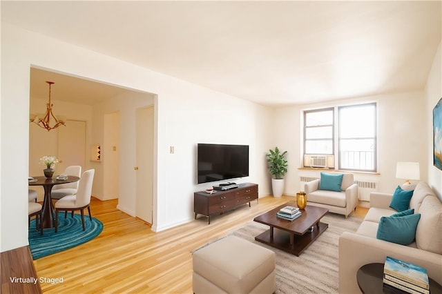 living room with light wood-type flooring, cooling unit, and radiator heating unit