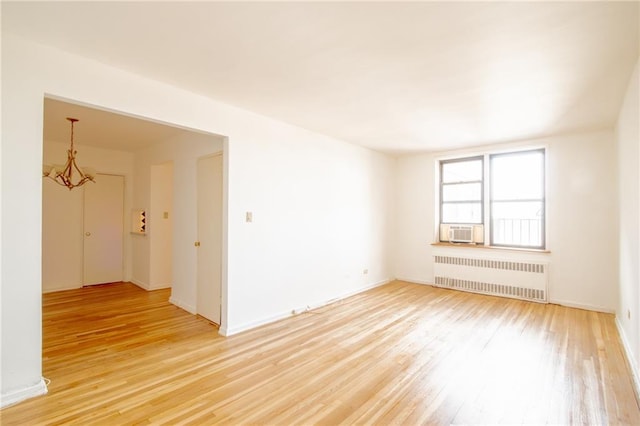 unfurnished room with radiator, light wood-style flooring, a chandelier, and cooling unit