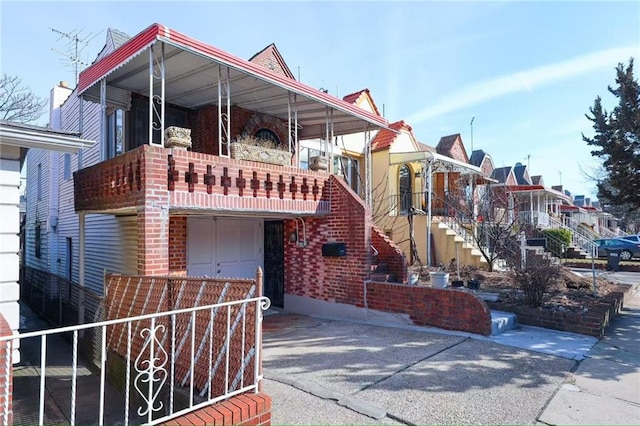 view of front of property with brick siding, a balcony, driveway, and a garage