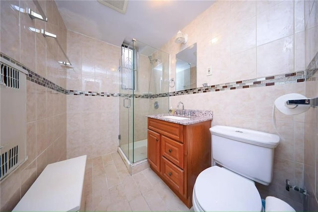 full bathroom with vanity, visible vents, a stall shower, tile walls, and toilet