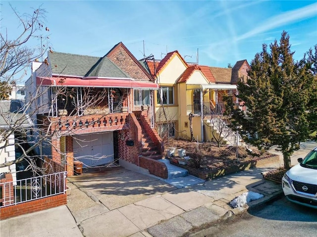 view of front of home with stairway, brick siding, driveway, and a tiled roof