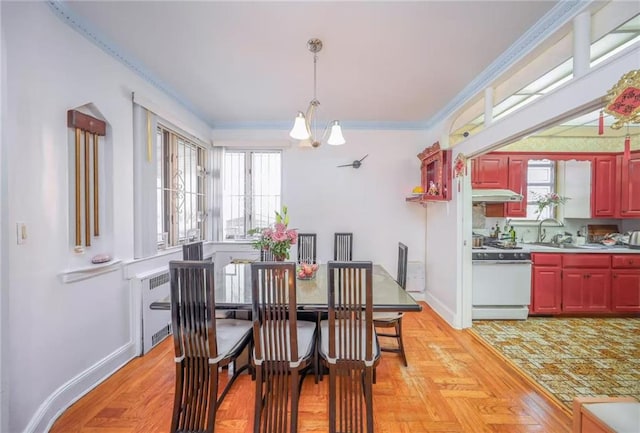 dining room featuring a notable chandelier, radiator, crown molding, and baseboards