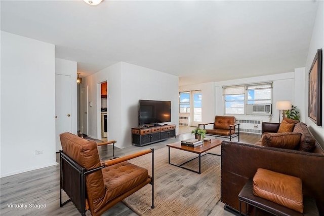 living area with a wall mounted AC, cooling unit, wood finished floors, and baseboards