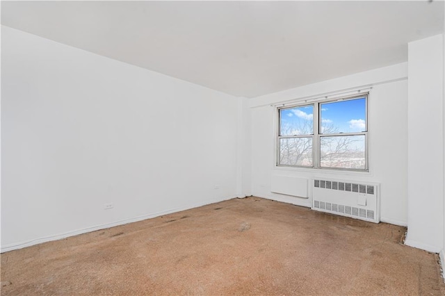 spare room featuring carpet and radiator