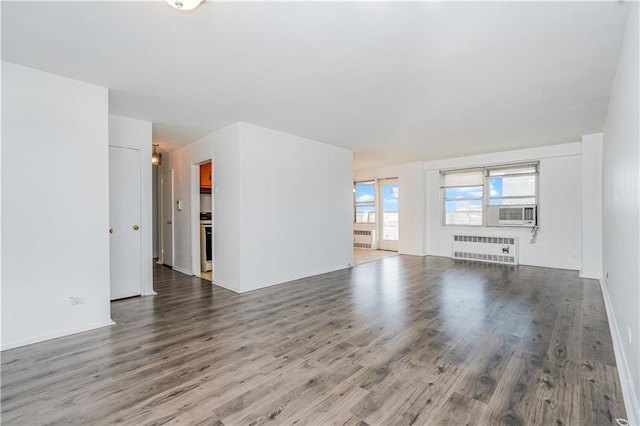 unfurnished living room with radiator heating unit, cooling unit, and wood finished floors