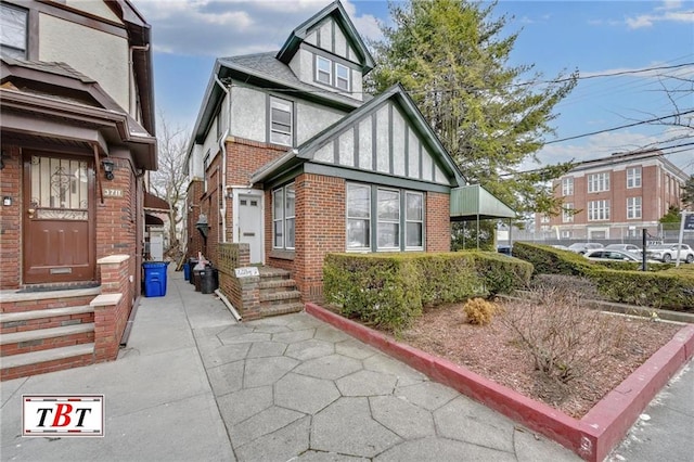 view of front of home featuring brick siding, a shingled roof, and stucco siding