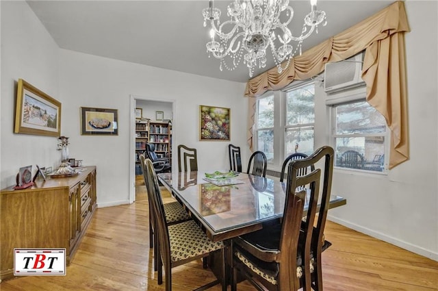 dining area featuring baseboards, light wood-type flooring, and an inviting chandelier