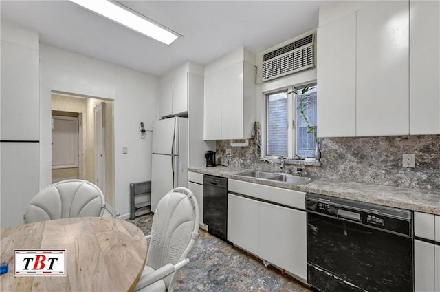 kitchen featuring black dishwasher, tasteful backsplash, a sink, and freestanding refrigerator