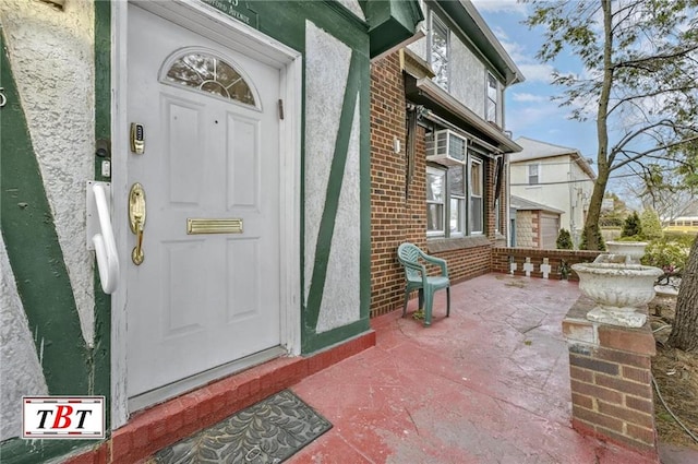 entrance to property with a patio, brick siding, and stucco siding