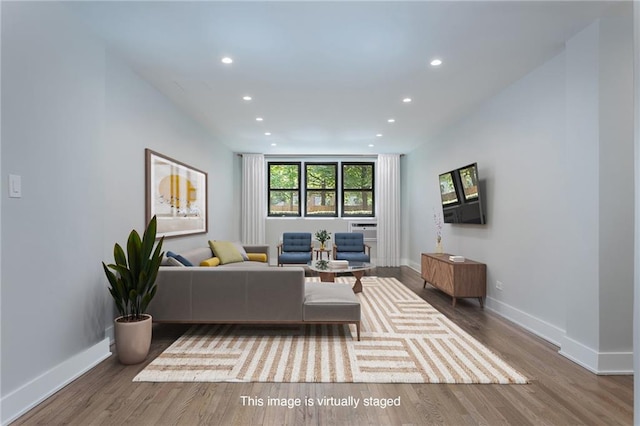 living area with baseboards, wood finished floors, and recessed lighting