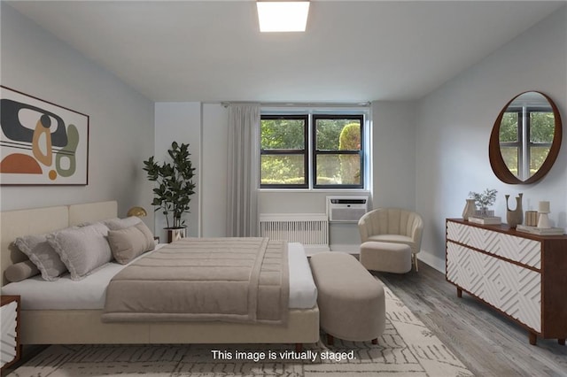 bedroom featuring radiator, wood finished floors, and an AC wall unit