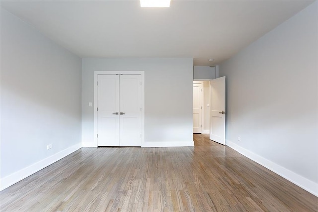 unfurnished bedroom with a closet, baseboards, and wood finished floors